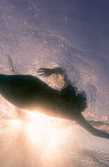 silhouette of a girl swimming at sea. seen from below. underwater.retro style