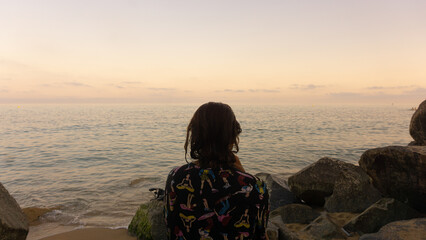 young brunette woman looking at the sunset over the ocean.Back view