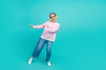 Full length photo of cool funky woman dressed pink pullover earphones dancing empty space isolated teal color background