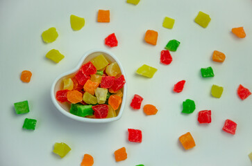 Colorful candied fruits in a plate on a white background and candied fruits scattered around