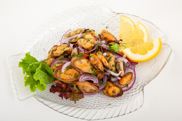 Salad with mussels and onion on a glass plate with lemon