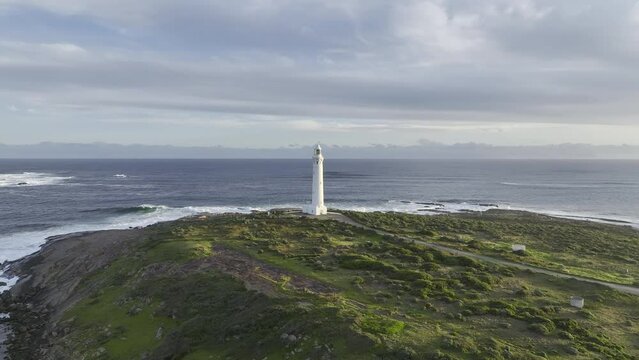 White lighthouse on rocky green coast in late afternoon in southern Western Australia. HDR ProRes aerial drone footage of Leeuwin Cape lighthouse in Augusta, WA.