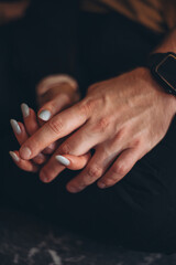 A woman's hand holds the fingers of a strong man's hand with her fingers.