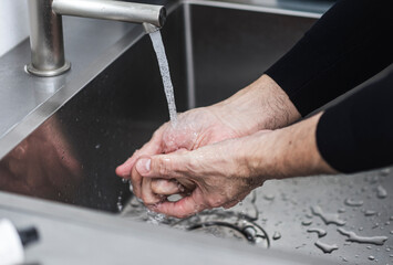 水道水で手を洗っている男性の手元のクローズアップ