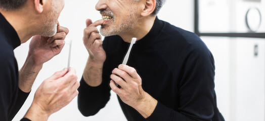 デンタルケア/鏡を見ながら歯茎をチェックする男性