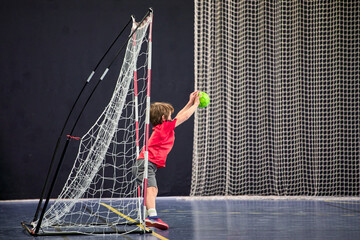 Détermination juvénile, enfant de huit ans gardien débutant arrêtant le ballon au handball