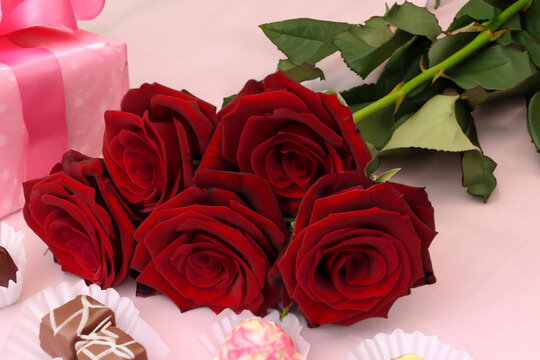 holiday gift. a bouquet of burgundy roses and chocolates in wrappers, a gift on the background. valentine's day concept