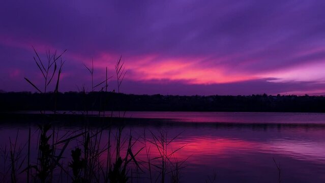Colorful clouds at sunset or sunrise. Landscape with a pink and purple sky above a lake.