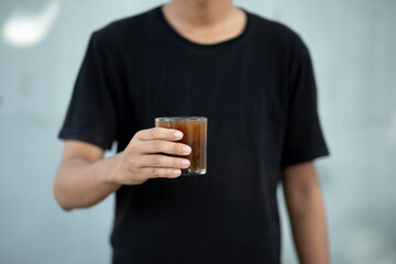 Closeup of a man hands holding a transparent coffee cup at home - obrazy, fototapety, plakaty