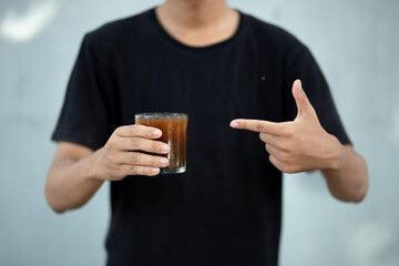 closeup of man hands holding a transparent coffee cup at home and pointing to a cu