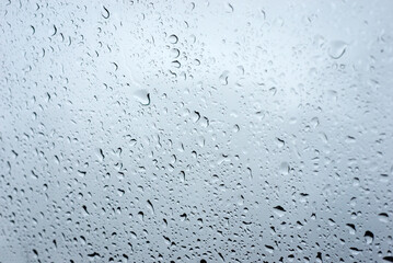 Obraz premium Closeup of rain drops on window on grey sky background