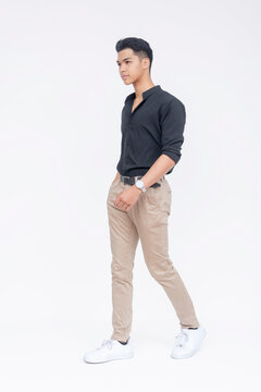 A stylish young Filipino man walks with confidence, dressed in a smart casual black shirt and khaki pants.