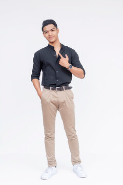 Stylish young Filipino man posing on a white background, exuding confidence and trendy casual style. Pointing to himself.