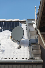 Satelittenschüssel im Winter auf schneebedecktem Dach mit Solaranlage - obrazy, fototapety, plakaty