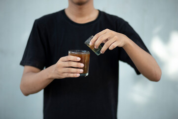 Front view close up of a man hands holding a coffee cup and liquid sugar at home