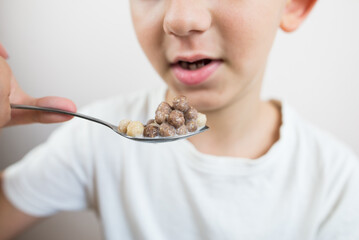 Close-up of a boy eating a delicious quick dry breakfast in the form of chocolate balls with milk.