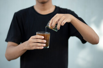 Front view close up of a man hands holding a coffee cup and liquid sugar at home