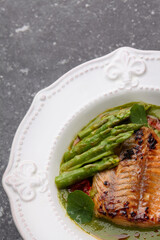Fried cod fish filet with green asparagus as close up on a plate