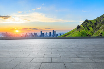 Empty square floor and green mountain with city skyline scenery at sunset