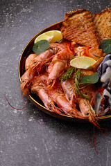 Roast Prawns Shrimps and mussels in a plate with le,mon and fried bread.Granite background. Close up