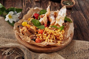 A delightful assortment of Eastern sweets featuring chak-chak, baklava, and khrustiki, arranged rustically on a wooden surface
