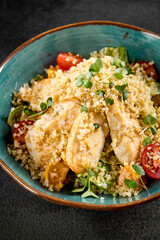 Quinoa salad with grilled chicken, cherry tomatoes, and greens in a turquoise ceramic bowl