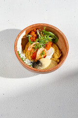 Scrambled omelet with shrimp, tomato salsa, and cheese mousse in a rustic bowl, a fusion of textures and flavors