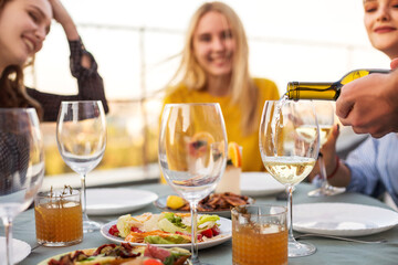 Happy friends waiting for waiter to pour wine