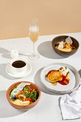 Breakfast spread with omelet, porridge, pancakes accompanied by coffee and sparkling wine
