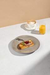 Elegant brioche with pâté and berry jam accompanied by coffee and orange juice on a minimalist table