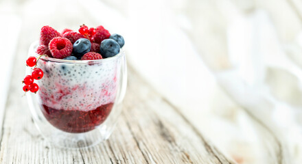 Dessert from yogurt with chia seeds, raspberries and blueberries on a old wooden background. top...