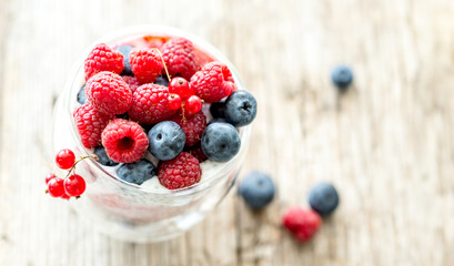 Dessert from yogurt with chia seeds, raspberries and blueberries on a old wooden background. top...