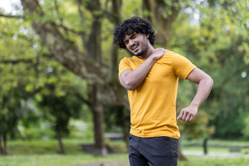 Active indian man feeling pain while working out in the park - healthy lifestyle concept