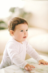 Fototapeta premium Portrait of adorable baby at home, wearing white onesie