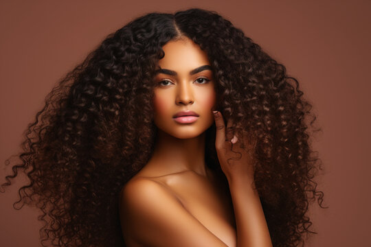 Hair care, beauty and black woman hand with curly hair on brown background in studio. Hair salon, wellness and girl holding curl marketing hair treatment products for growth, natural and healthy hair 