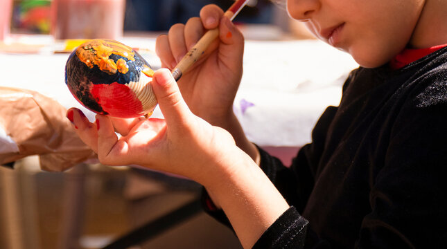 Child girl painting Easter egg. Child on Easter day