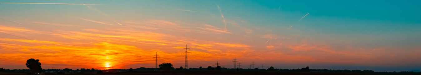 High resolution stitched alpine summer sunset panorama with overland high voltage lines near...