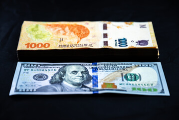 Comparison of a stack of 1000 Argentine peso notes with a 100 US dollar note. Inflation. Consequences of the monetary issue in Argentina. - obrazy, fototapety, plakaty