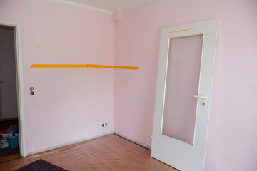 Walls of a room during renovation, a door is suspended from the wall