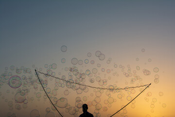 A man makes lots of soap bubbles with a bubble stick