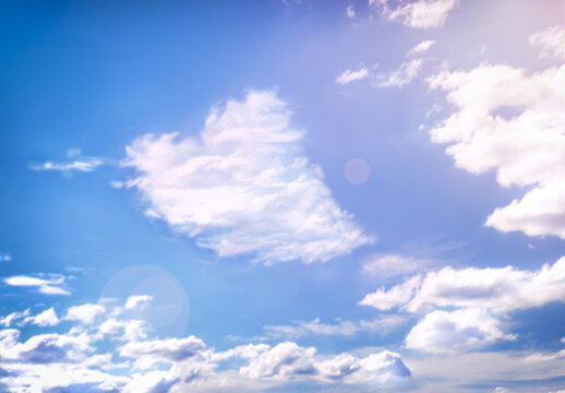 Fluffy clouds forming a heart shape on blue sky with sun, soft focus. Heavenly clouds background. Valentine day, love, romantic, Mother day concept. Copy space. Empty place for message.
