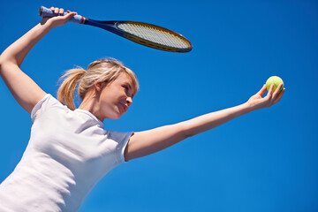 Tennis, serving and woman in game for sport, competition and playing with ball and racket on blue sky. Athlete, exercise and training outdoor with challenge on court in summer match and contest