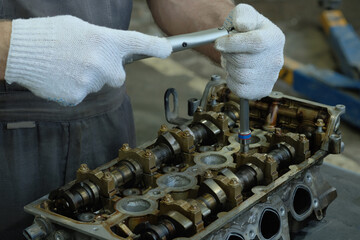 Car engine repair. An auto mechanic performs the work of installing camshafts.