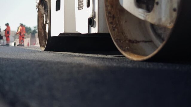 Compactor is driving over freshly poured asphalt and compresses it on the road to fix a hole