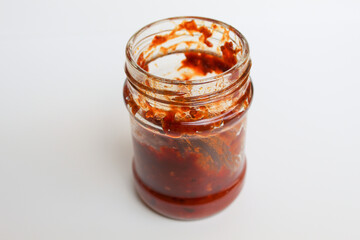 Sambal is an Indonesian chilli sauce or paste. In a transparent glass jar. Isolated on white background
