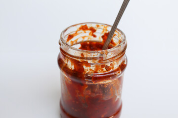 Sambal is an Indonesian chilli sauce or paste. In a transparent glass jar. Isolated on white background