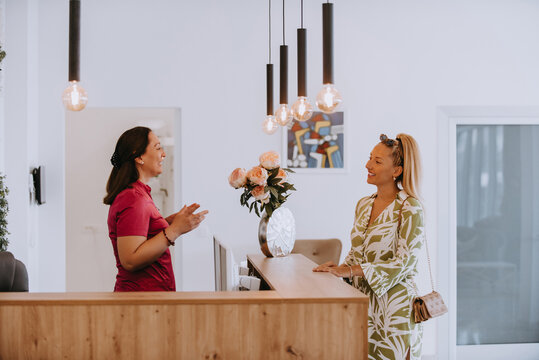 A beautiful blonde woman conversing with the dental clinic receptionist, scheduling an appointment for dental treatment with a bright smile