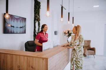 A beautiful blonde woman conversing with the dental clinic receptionist, scheduling an appointment for dental treatment with a bright smile - obrazy, fototapety, plakaty