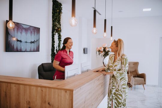 A beautiful blonde woman conversing with the dental clinic receptionist, scheduling an appointment for dental treatment with a bright smile