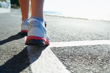 Feet, rear view and runner on street for sports, health or cardio training in preparation or marathon. Fitness, exercise and running shoes with athlete person on road for workout, performance or race